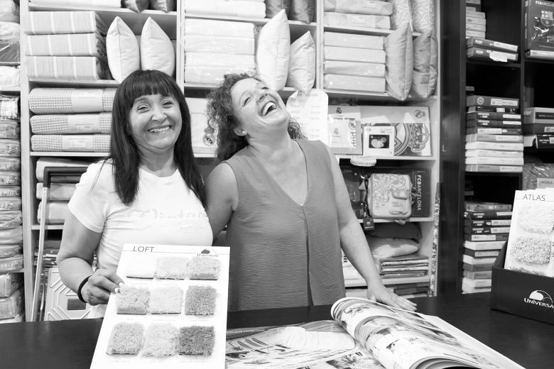 Trabajadoras riendo detrás del mostrador con foto en blanco y negro 