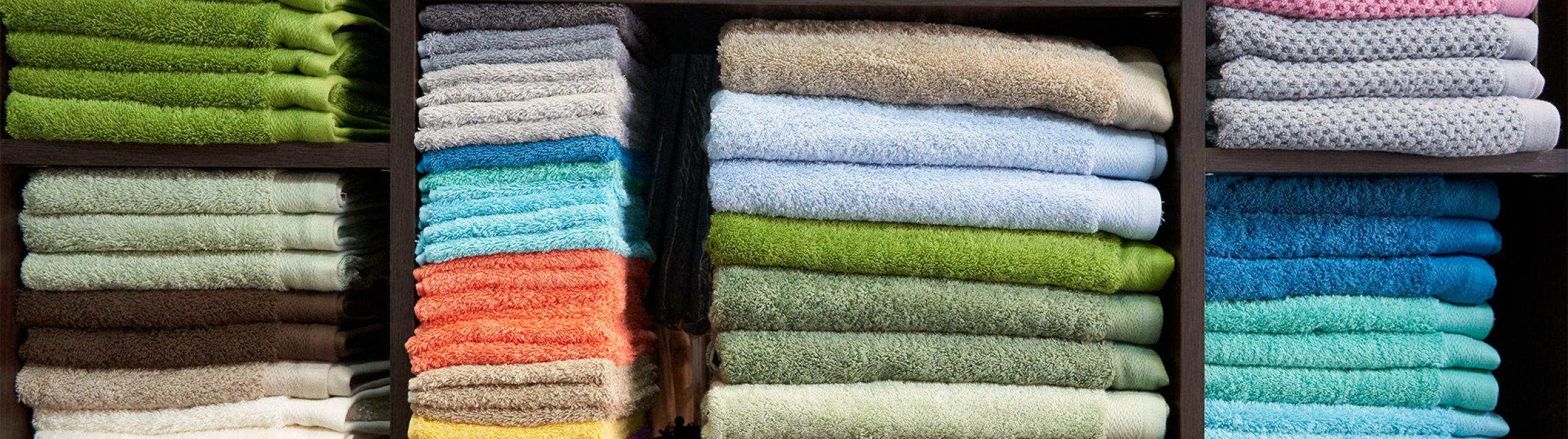 Imagen de una estantería llena de diferentes toallas de colores 